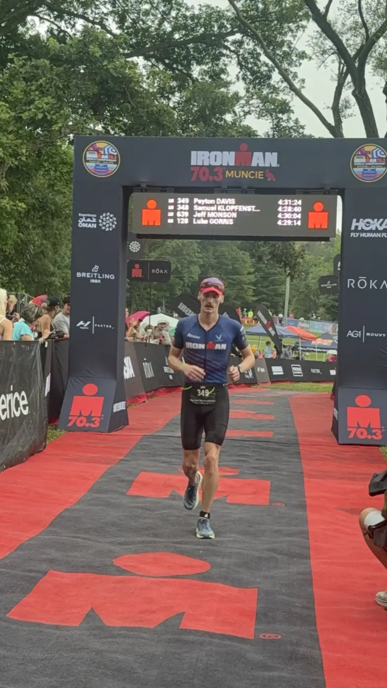 A teammate running through the finish arch of an Ironman 70.3.